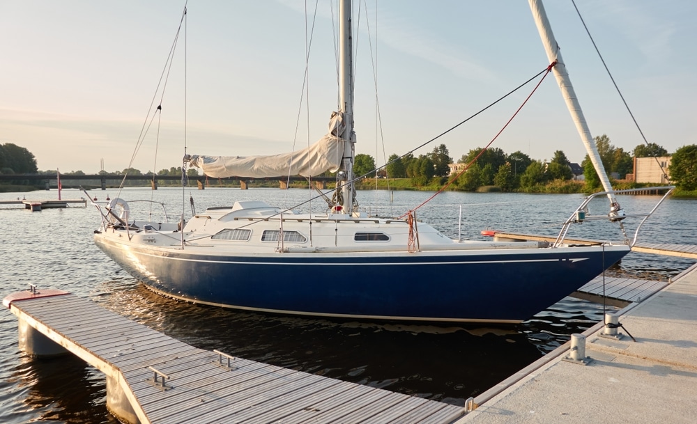 Sloop rigged sailboat (for rent and sale) moored to a pier in a yacht marina.