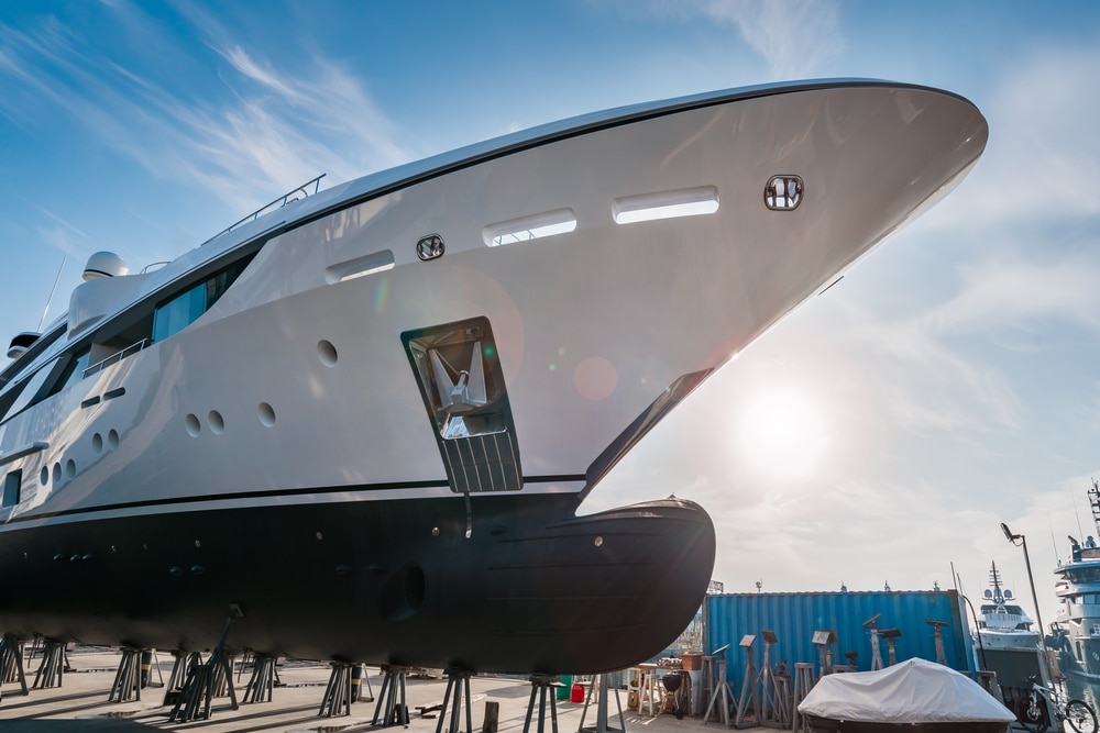 Wide shot of the bow of a new white modern superyacht on dry dock