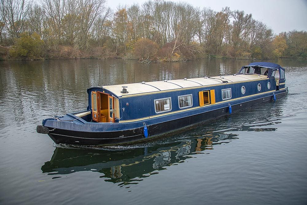 a blue colored boat with a wide beam in the water