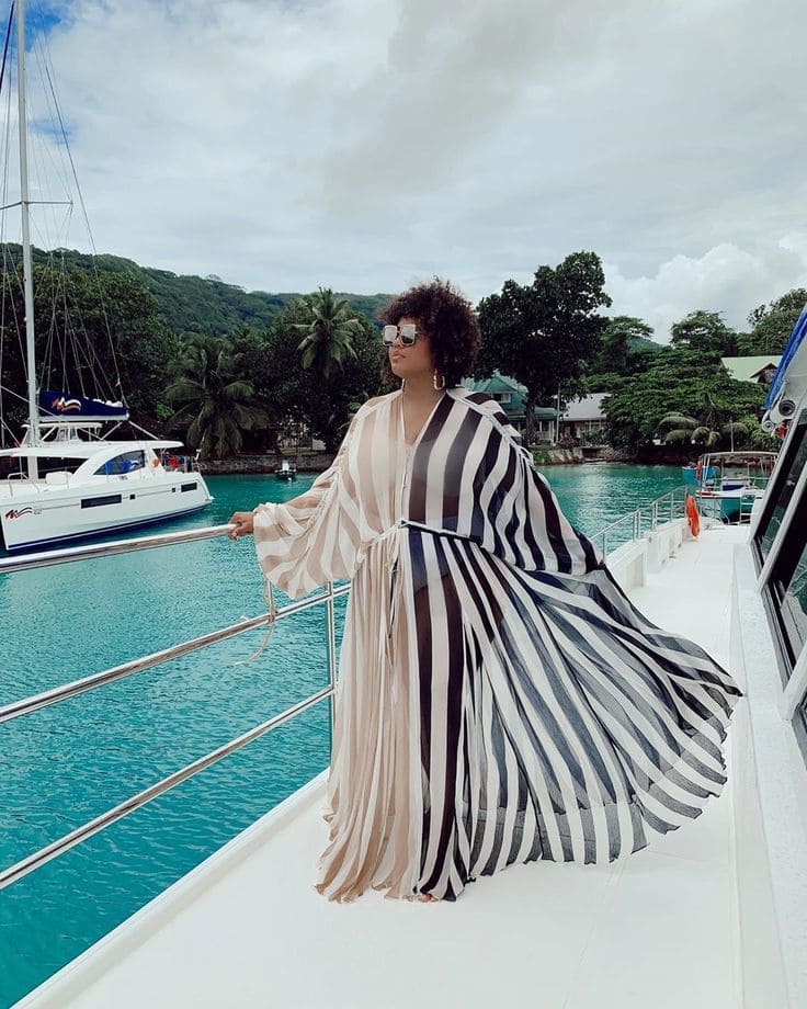 a women wearing black and fawn stripped dress standing in a boat