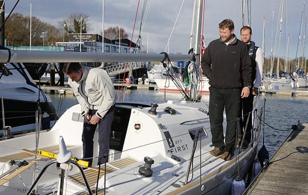 3 people checking and measuring various parts of a white boat