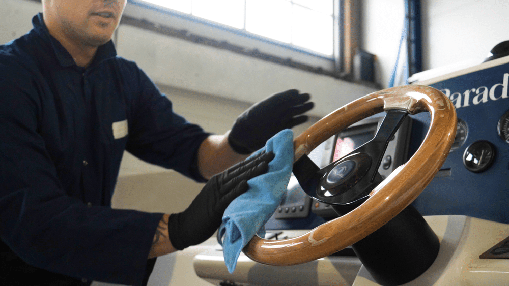 A view of a person cleaning a shiny boat steering wheel