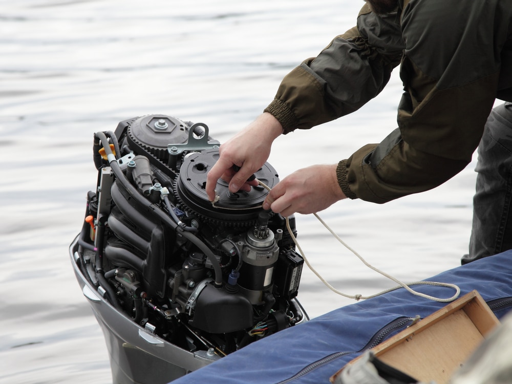 A view of a person handstarting a motor on the transom