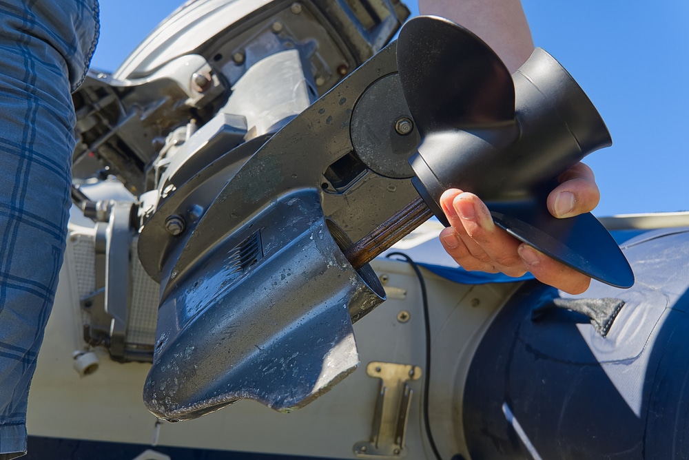 A view of a person holding a boat outward propeller on the stern side