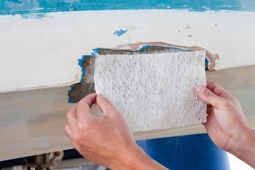 A view of a worker adding a fibreglass sheet to a boat material