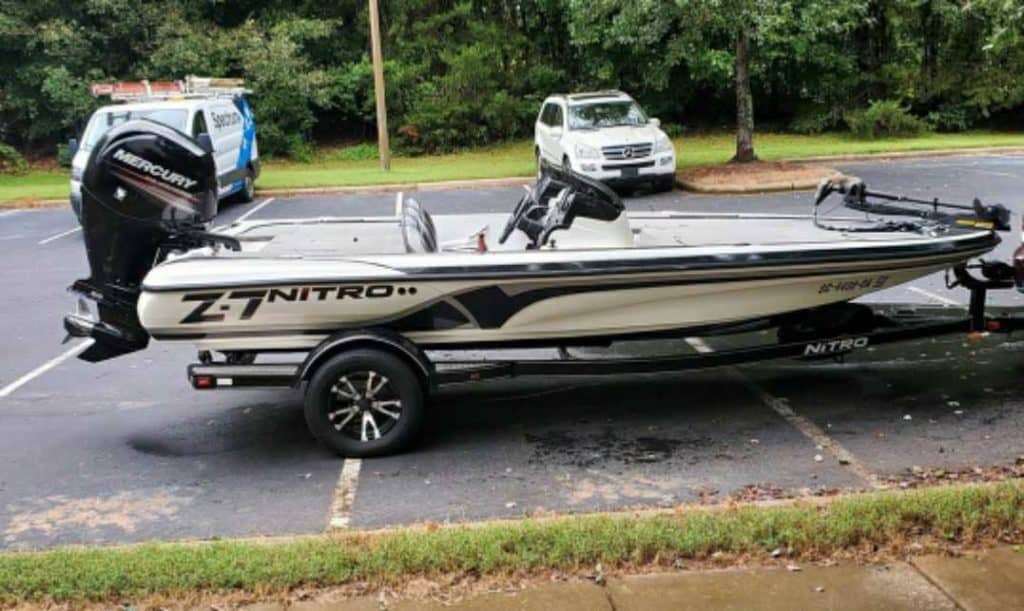 A side view of a bass boat on a road