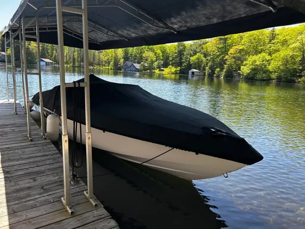 A view of a boat with a black cover in waters with a sun shed over it