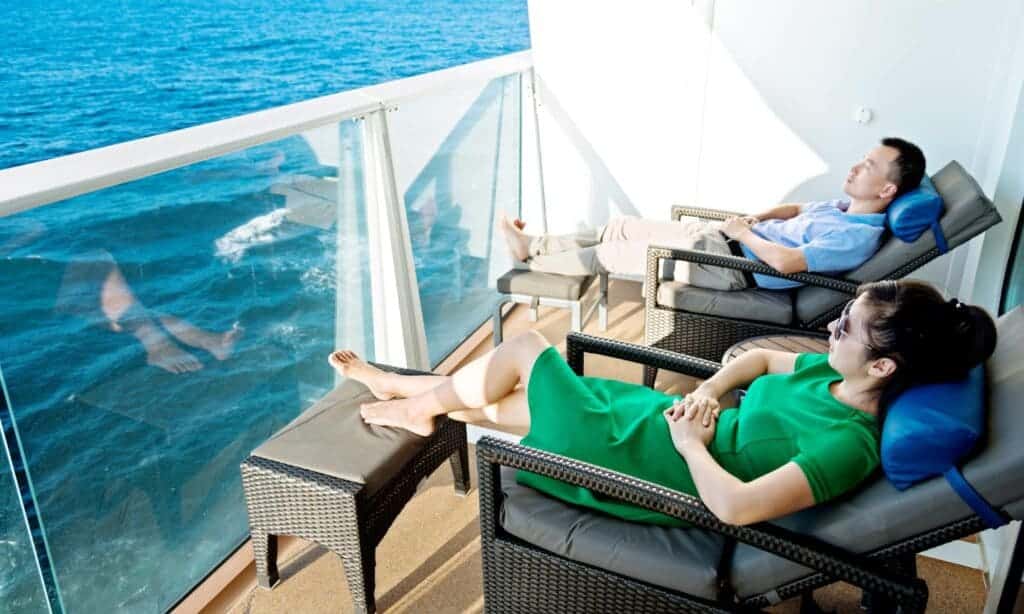 A view of a man and woman relaxing by the port side in a cruise ship