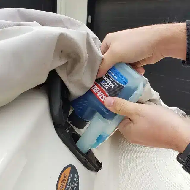 A view of a person adding fuel stabilizer to a boat tank