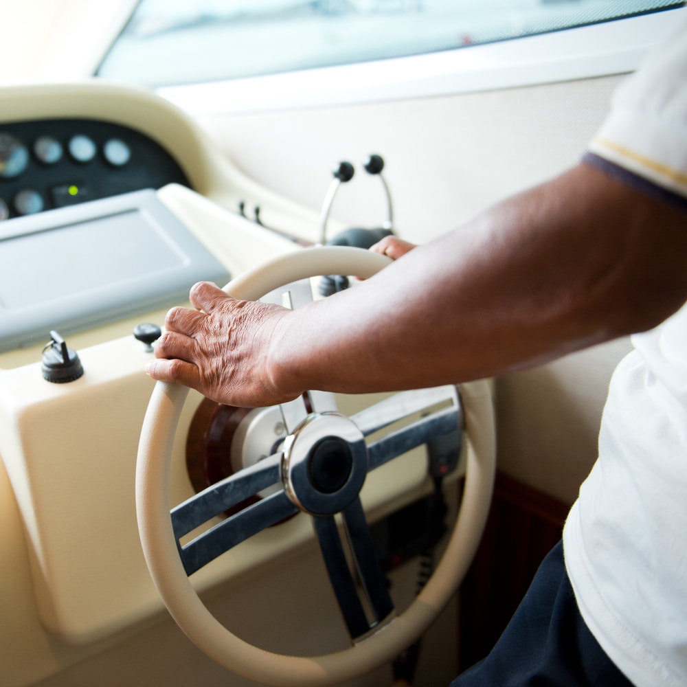 A view of a person holding a boat wheel